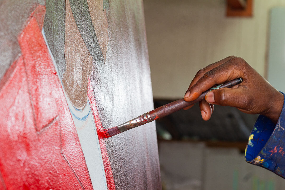 Close up of Shakes Tembani's hand as he paints a portrait painting